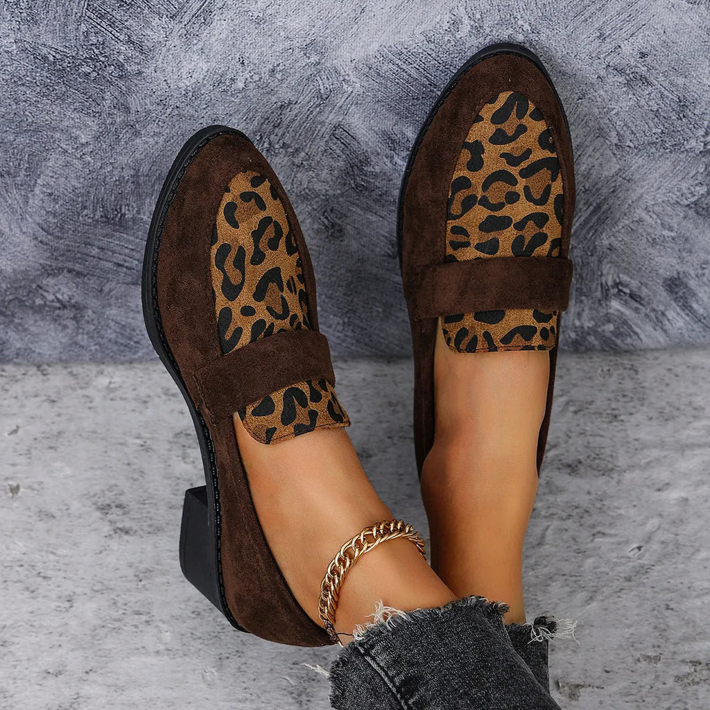 Women's leopard print suede slip-on shoe with a chunky mid heel and pointed toe on a brown background.