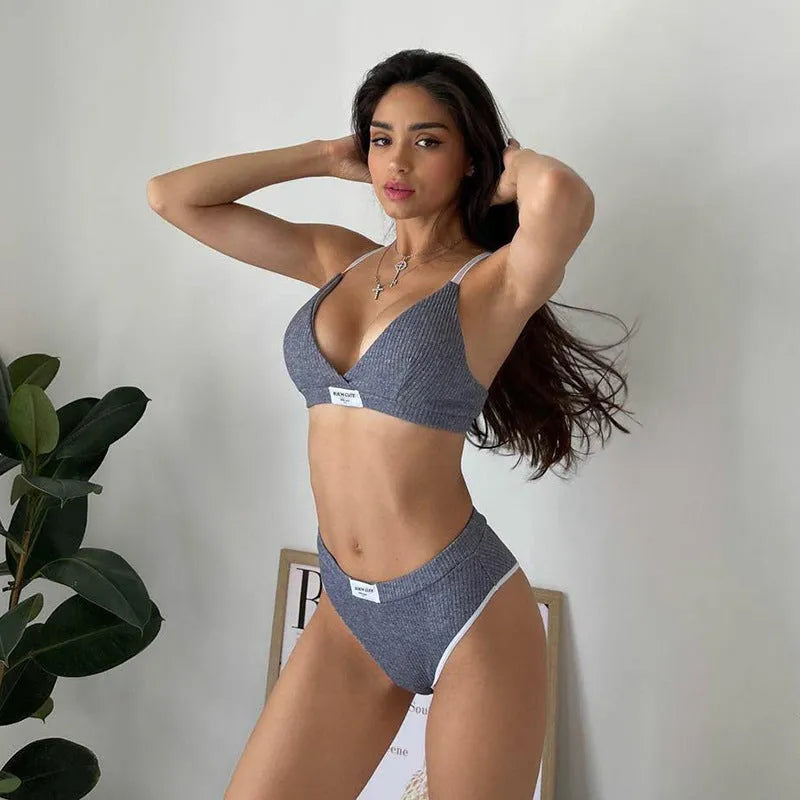 Women's black bikini set with white embroidered contrast binding letters on sleeveless top and shorts.