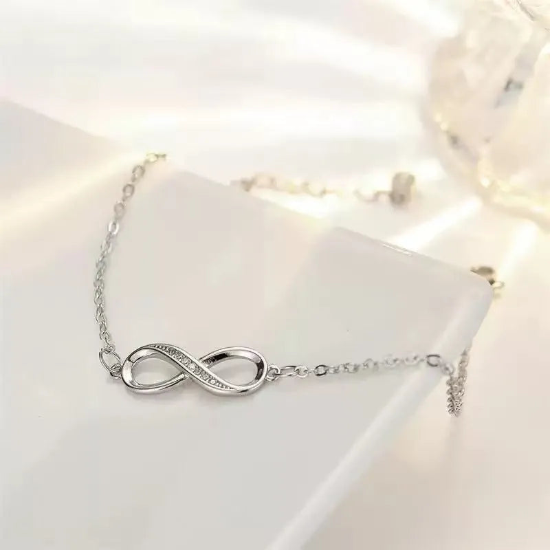 Silver copper Mobius strip diamond ring push-pull bracelet with lucky cat charm on display.
