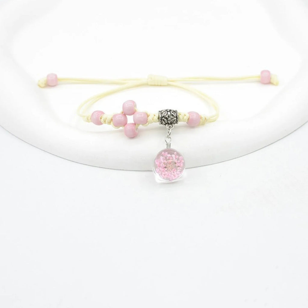 Close-up of a women's glass bracelet with real dried flowers inside, showing large 1.4 cm beads in a blue colour.