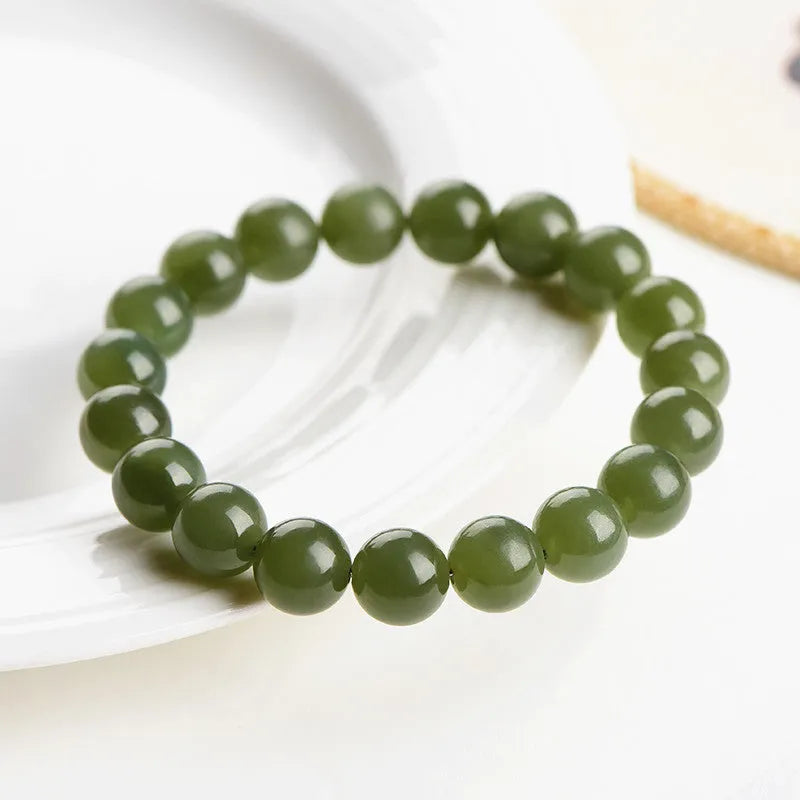 Polished Hetian jade ball bracelet with ice-like translucent beads in spherical shapes on a plain background