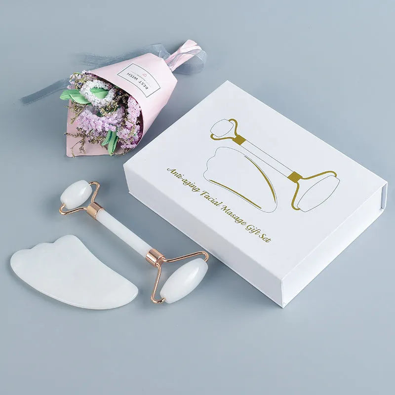 White jade facial roller and Gua Sha scraping board set on a plain surface.