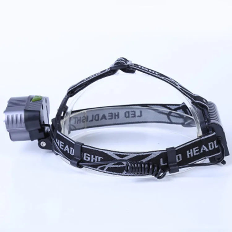 Fixed focus camping head torch with long range beam on a headband, shown with its rechargeable battery and charger.