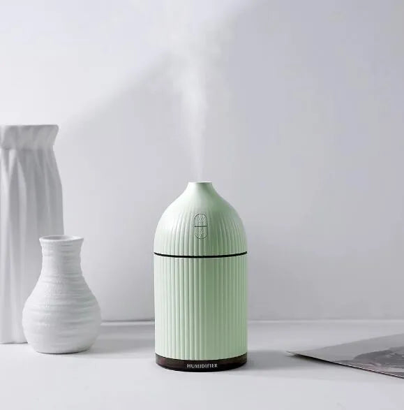 White ultrasonic aromatherapy diffuser and humidifier with LED light on a wooden surface