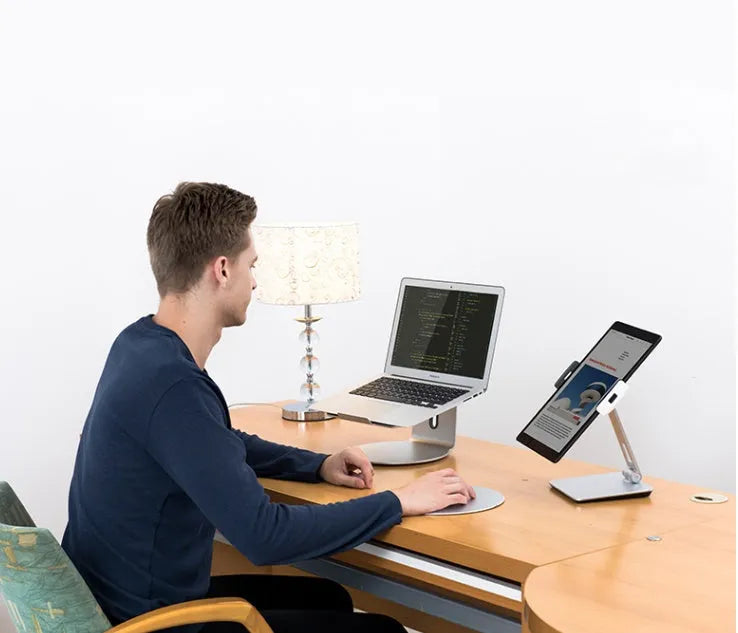 Silver folding aluminium phone and tablet stand with 360° rotation on wooden desk