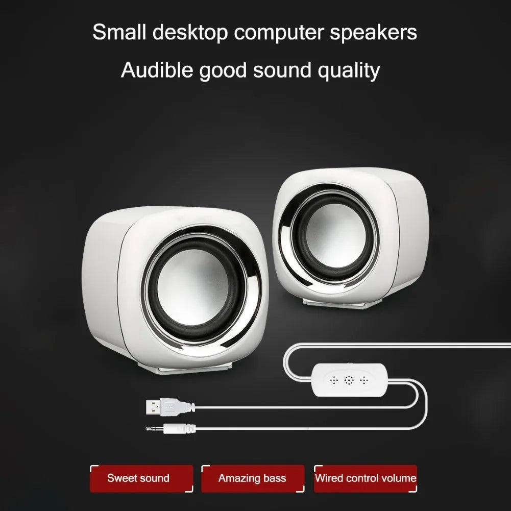 Pair of black wired mini desktop computer speakers with 3.5mm plug and scroll wheel volume control on a desk
