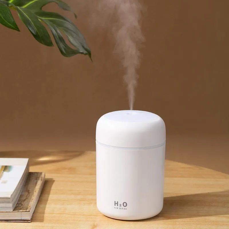 Pink USB desktop humidifier with mood lights and water tank on a wooden desk
