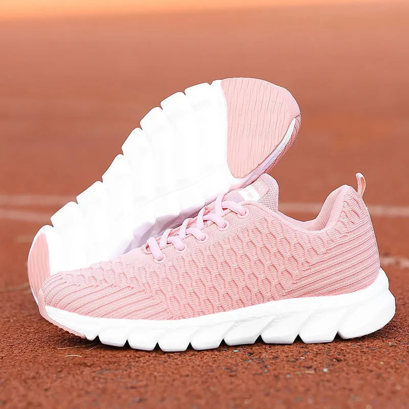 Women's running shoes in black, pink, and white with a fly weave upper and durable outsole.