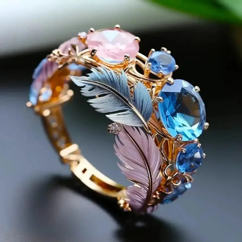 Gold-colour geometric brass ring with embossed feather design and inlaid zircon stone.