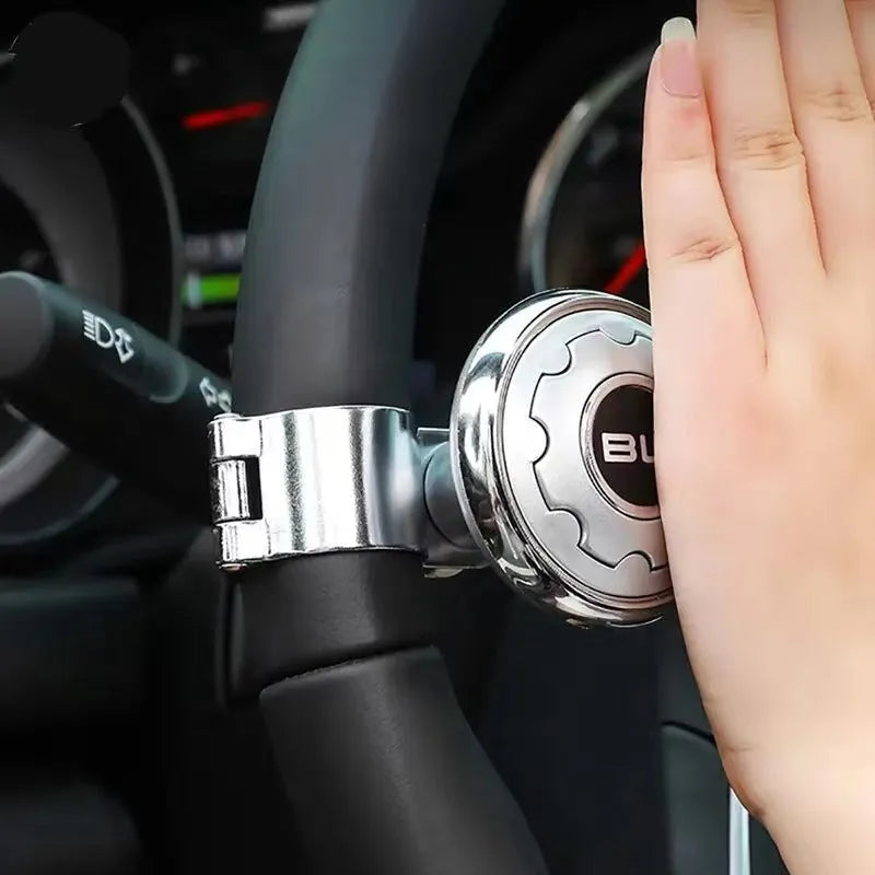 Metal universal steering wheel assist ball with steel ball bearing in silver finish mounted on a car steering wheel for one-handed control