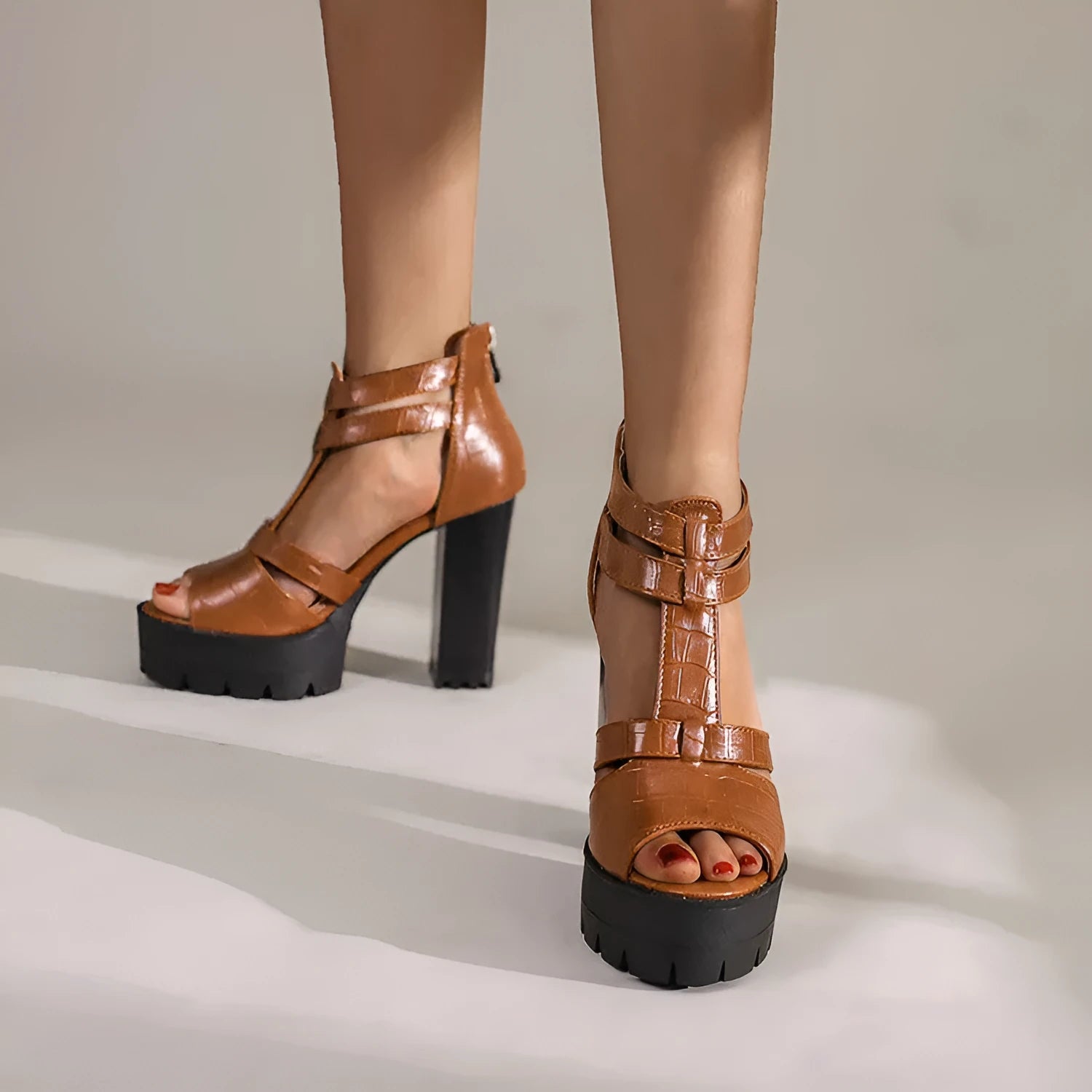 Black platform high heel sandals with round head and back zipper on plain background