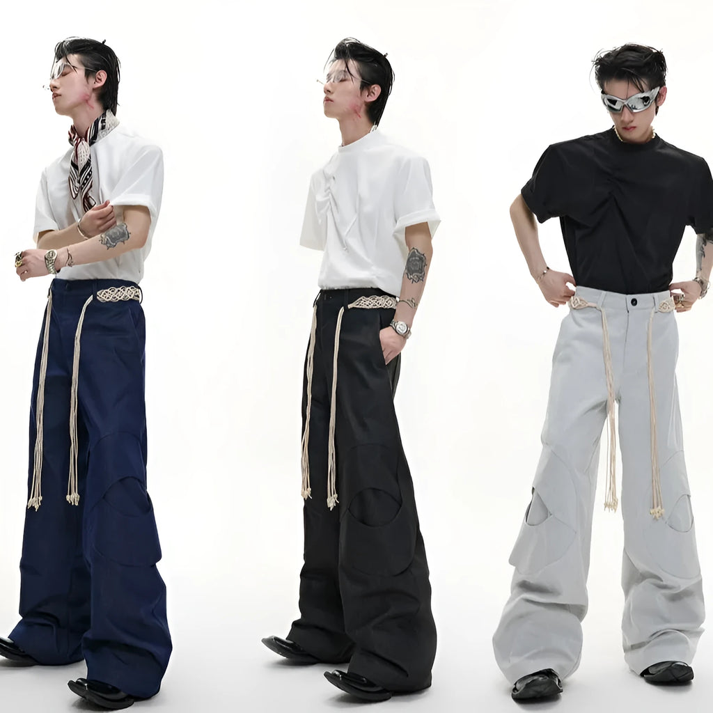 Men's dark blue loose fit straight-leg trousers showing 3D cutting, belt stitching, and tassel details on pockets and zipper.