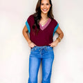 Burgundy women's loose V-neck sweater with contrast trim on short cuffed sleeves.