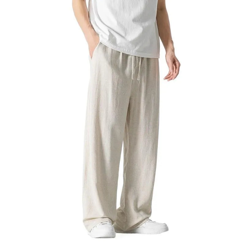 Men's beige loose straight-leg linen trousers with a drawstring waist on a neutral background.