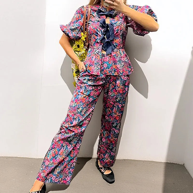 Women's floral print trouser suit with tie-neck blouse featuring puff sleeves