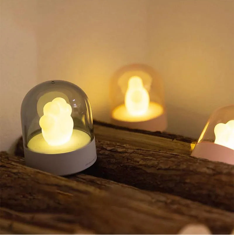Grey cat paw shaped musical night light with USB charging cable on wooden desktop