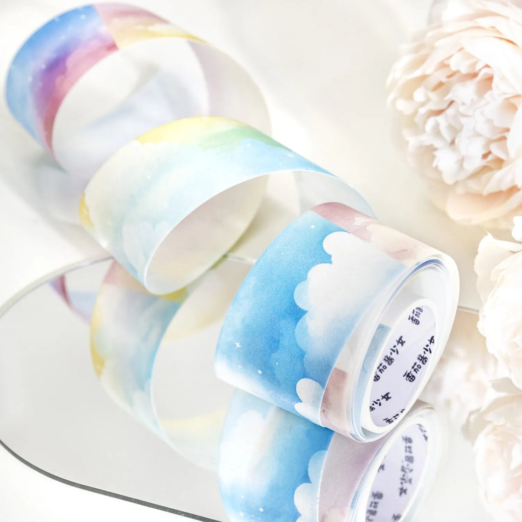 Roll of Japanese paper decorative washi tape with sky theme designs, showing colourful clouds, sunny day, and twilight patterns.