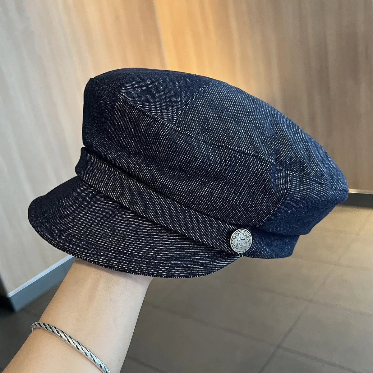 Adjustable octagonal denim newsboy hat in dark blue with contrast brim on white background