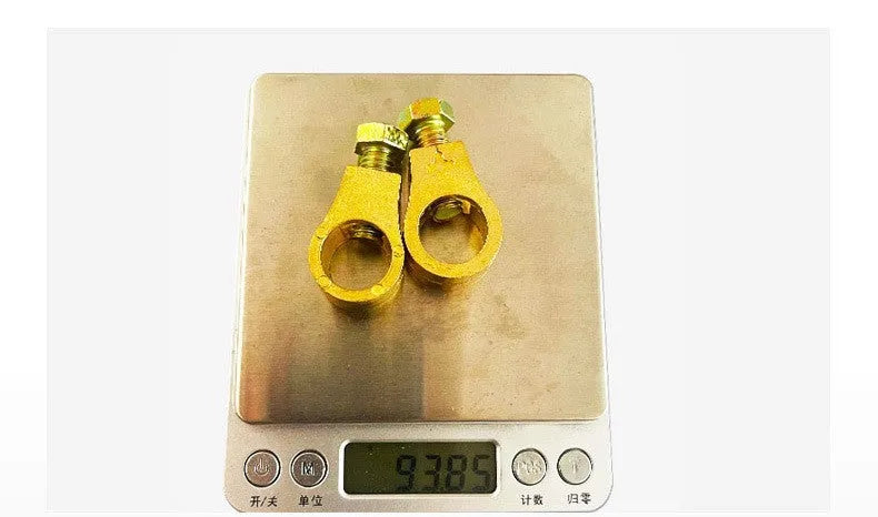 Solid copper car battery cable terminal clamp with brass bolts and a black plastic protective cover.