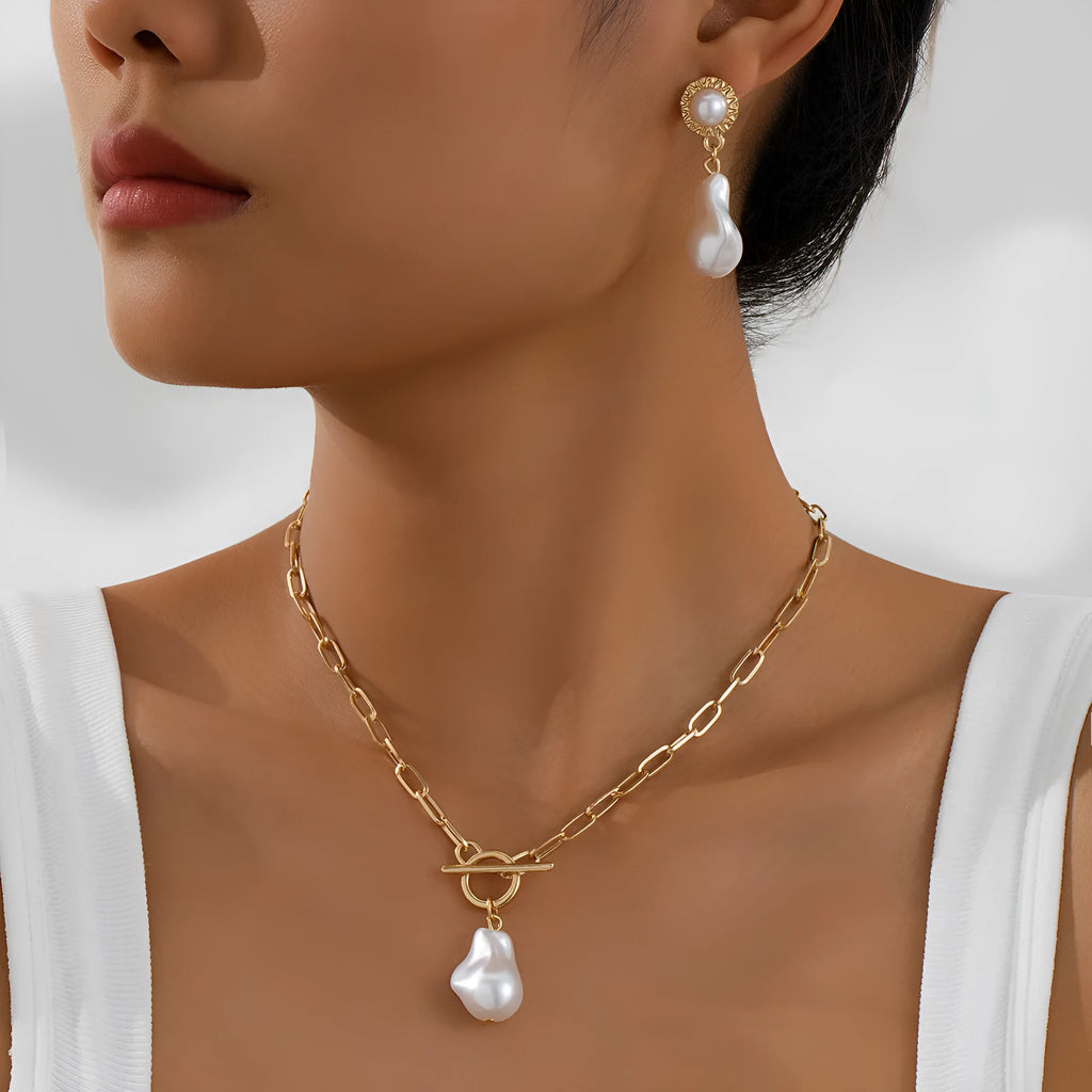 Gold tone baroque pearl pendant necklace and matching ear stud set on display