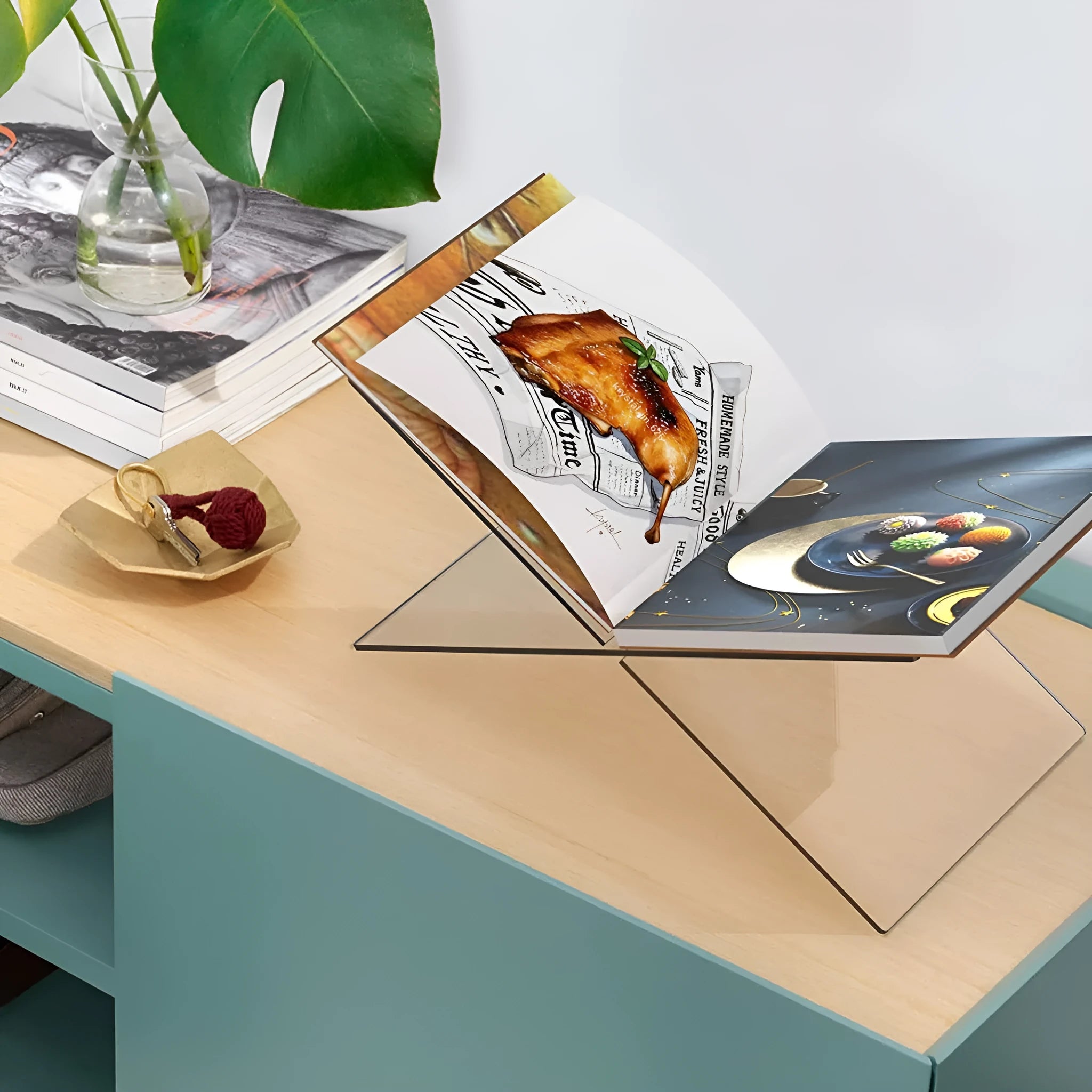 Clear acrylic X-shaped book reading rack holding an open book on a desk.