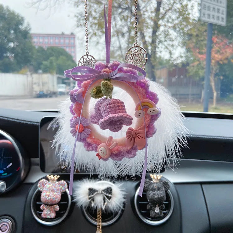Handwoven wool bell orchid car pendant in green, hanging from a rear-view mirror.
