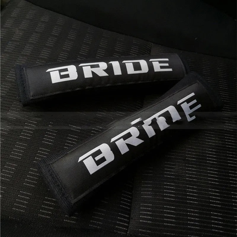Pair of black car seatbelt shoulder pads made from cotton sponge cloth, showing embroidery detail.
