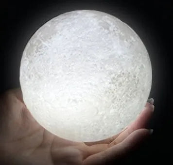 3D printed white moon lamp on a wooden stand with a glowing centre.