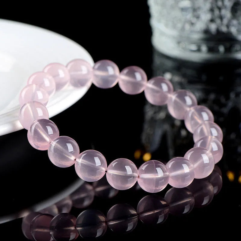 Women's natural starlight crystal round bead bracelet in pink on a white background.