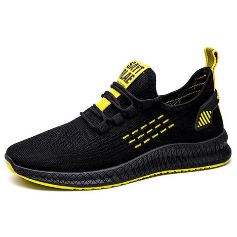 Men's black low-top casual sneakers with flying weave upper and cross strap detail on a white background.
