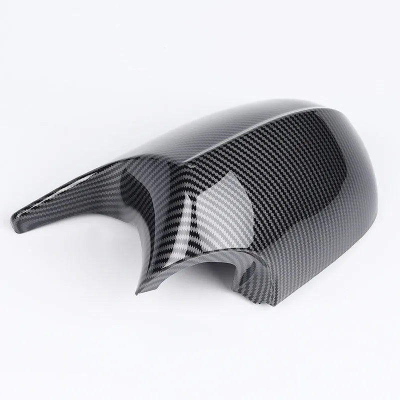 A pair of black and carbon pattern ABS plastic rearview mirror housing shells for a BMW 3 Series E90.