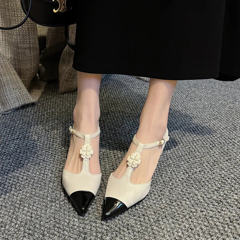 Women's black stiletto heel shoe with pointed toe, floral buckle detail, and a mid-height heel