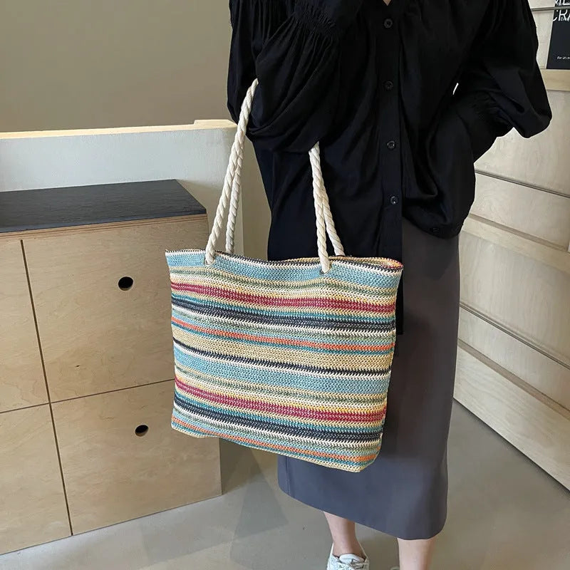 Blue woven shoulder bag with straw and nylon construction showing adjustable straps and textured exterior