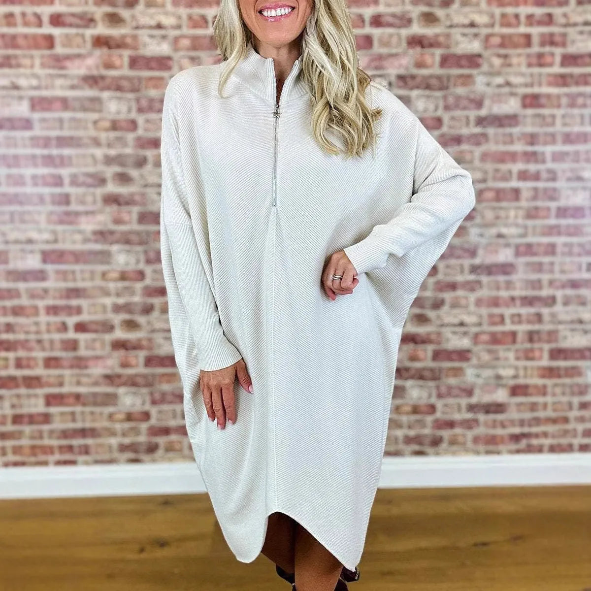A woman wearing a solid colour loose knitted dress with raglan sleeves, shown in one of five available colours.