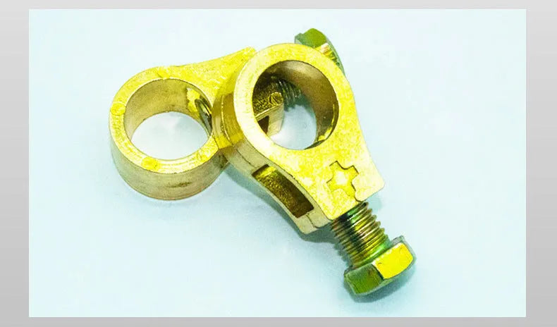 Solid copper car battery cable terminal clamp with brass bolts and a black plastic protective cover.