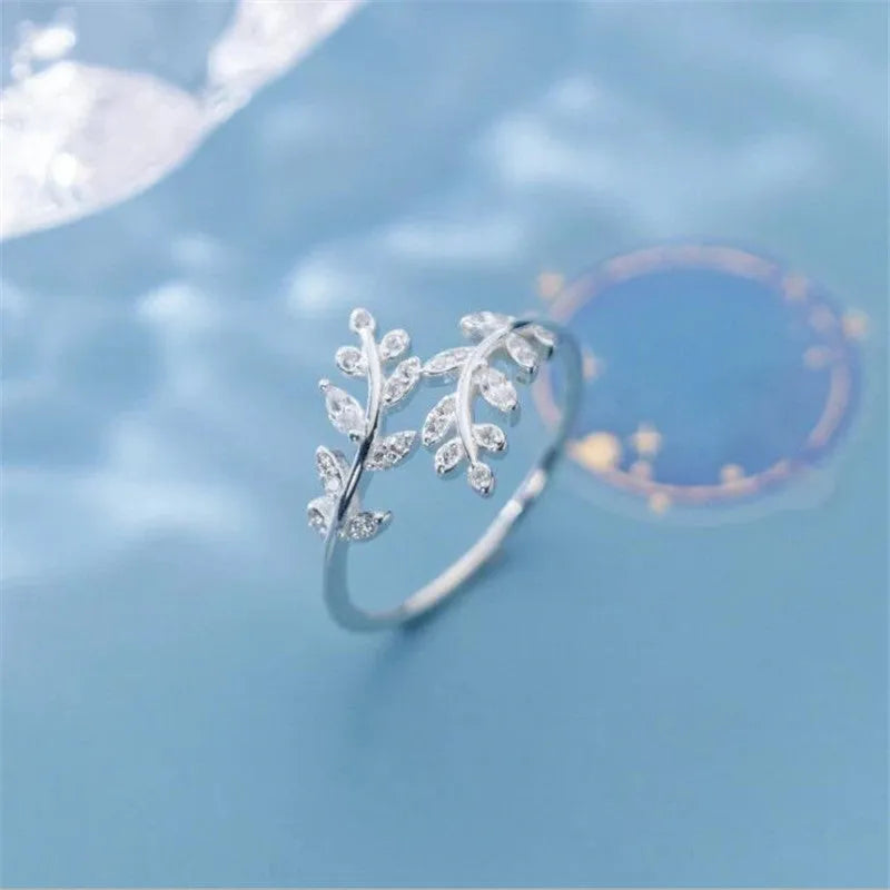 Gold and silver women's branch leaf fashion ring with geometric design on a plain background.