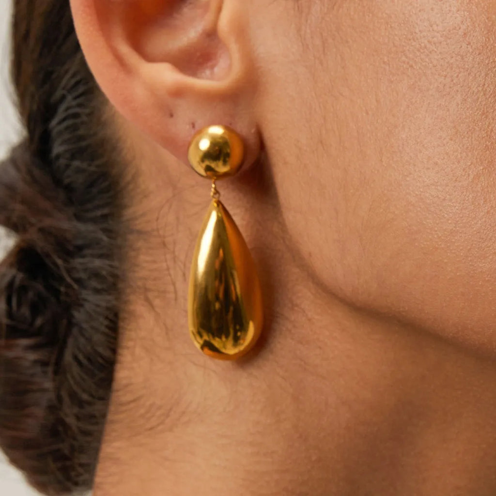 Gold electroplated stainless steel earrings with a geometric hemisphere and water drop pendant.