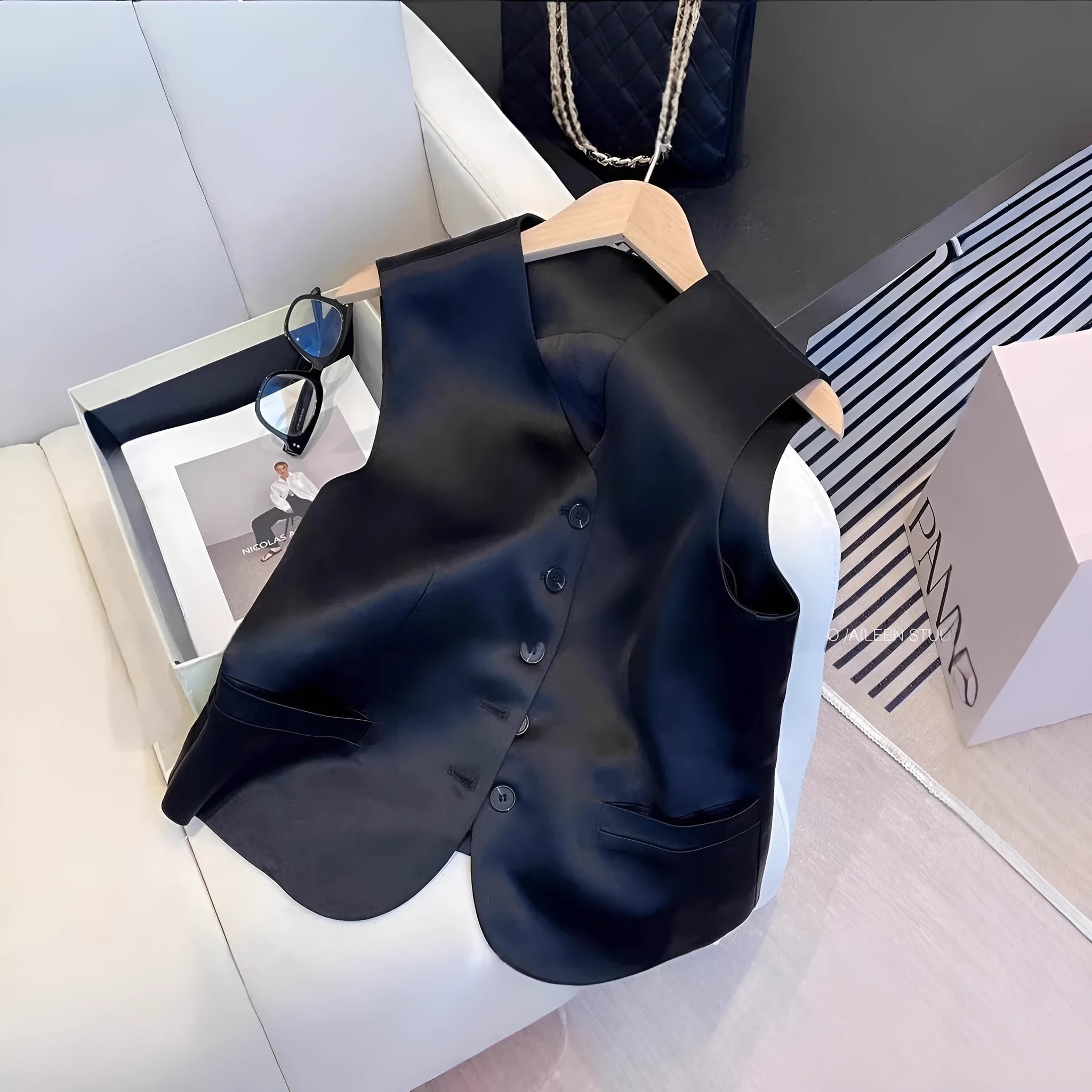 Black sleeveless satin vest for women on a hanger, showing loose fit and splicing detail.