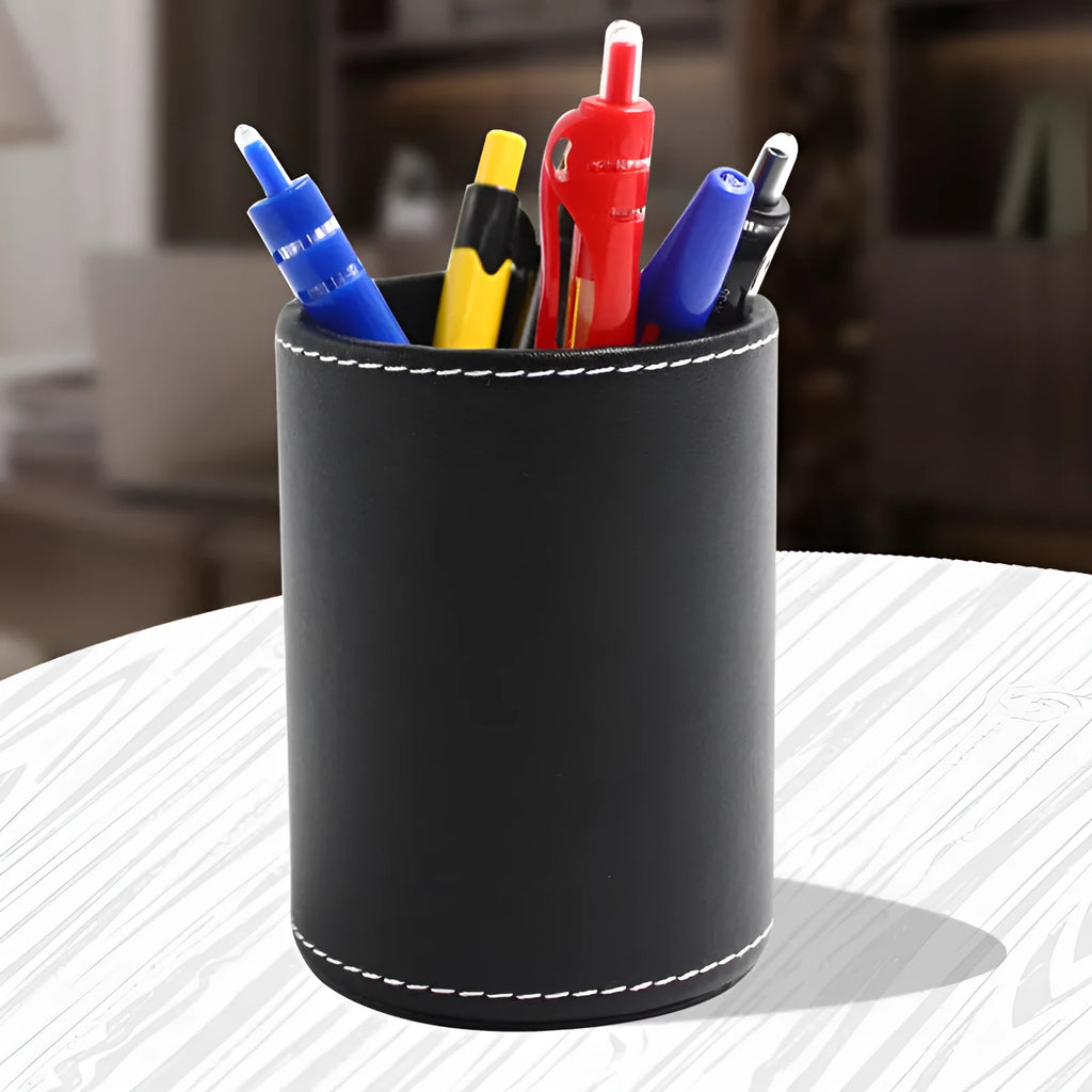 Round black leather pen holder on desk with pens