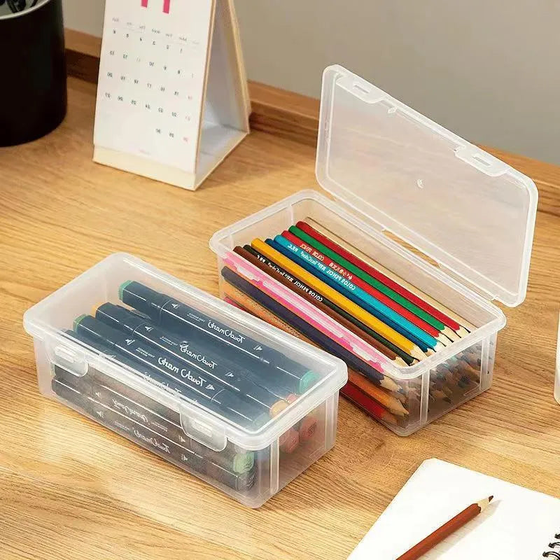 Clear plastic stationery storage box full of coloured pencils and drawing tools on a table.
