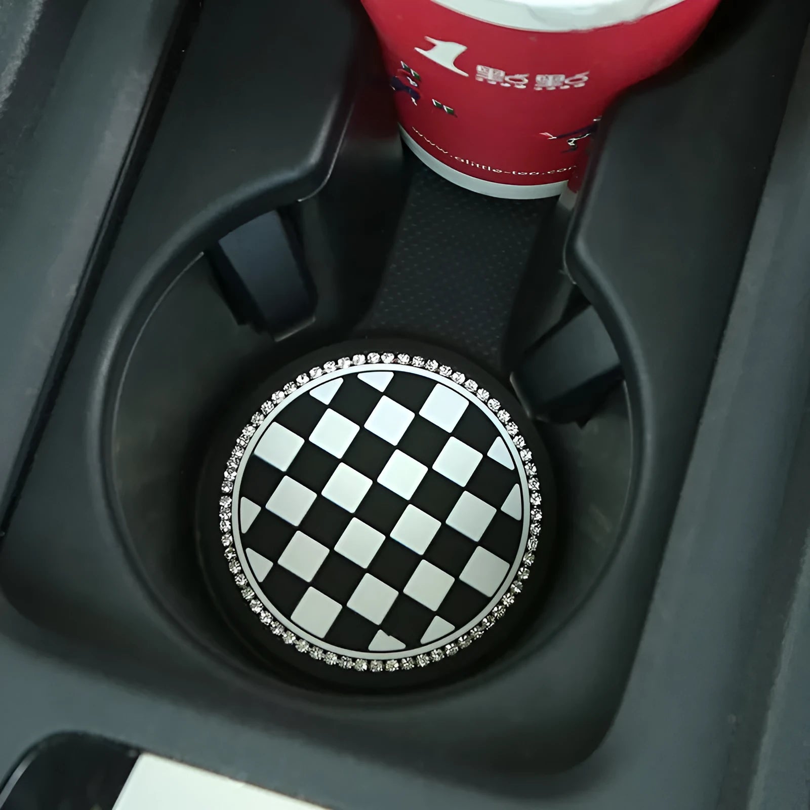 Plastic car water cup mat in black and white checkerboard with drill detailing on a non-slip surface for cup holder use