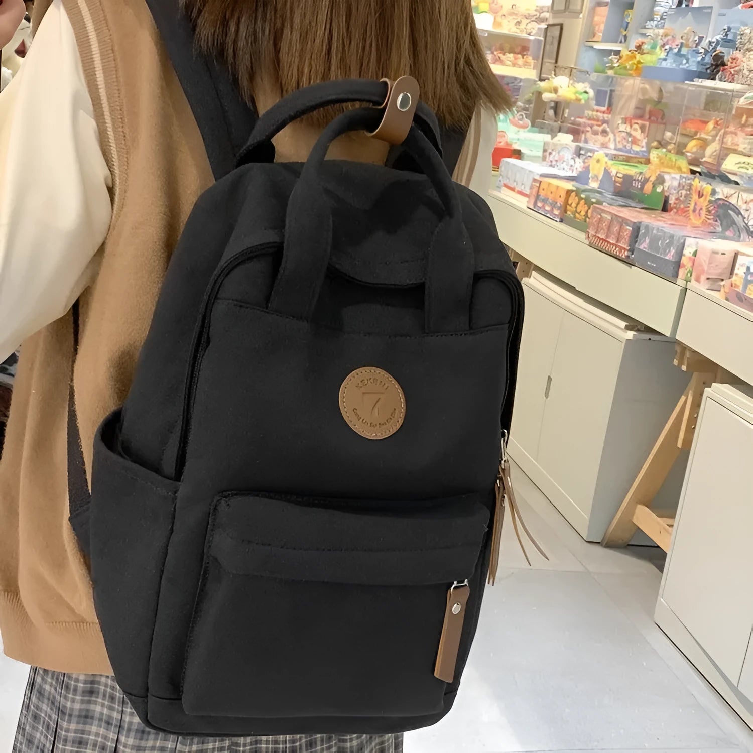 Solid black Oxford cloth fashion backpack with retro sewing thread details and curved shoulder strap for school and travel.