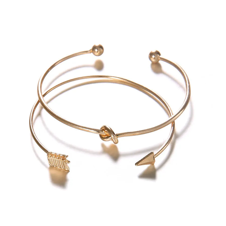 Gold-coloured women's vintage cuff bracelet with an arrow and knotted design motif.