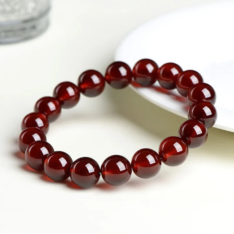 Natural orange red garnet ball bracelet with Ruyi elements on a wrist, showing retro unisex design.