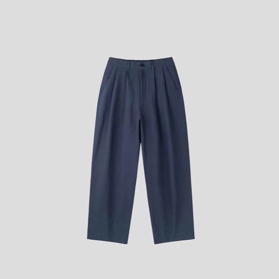 Men's lightweight apricot coloured loose-fit linen trousers laid flat, showing zip fly and relaxed leg style.