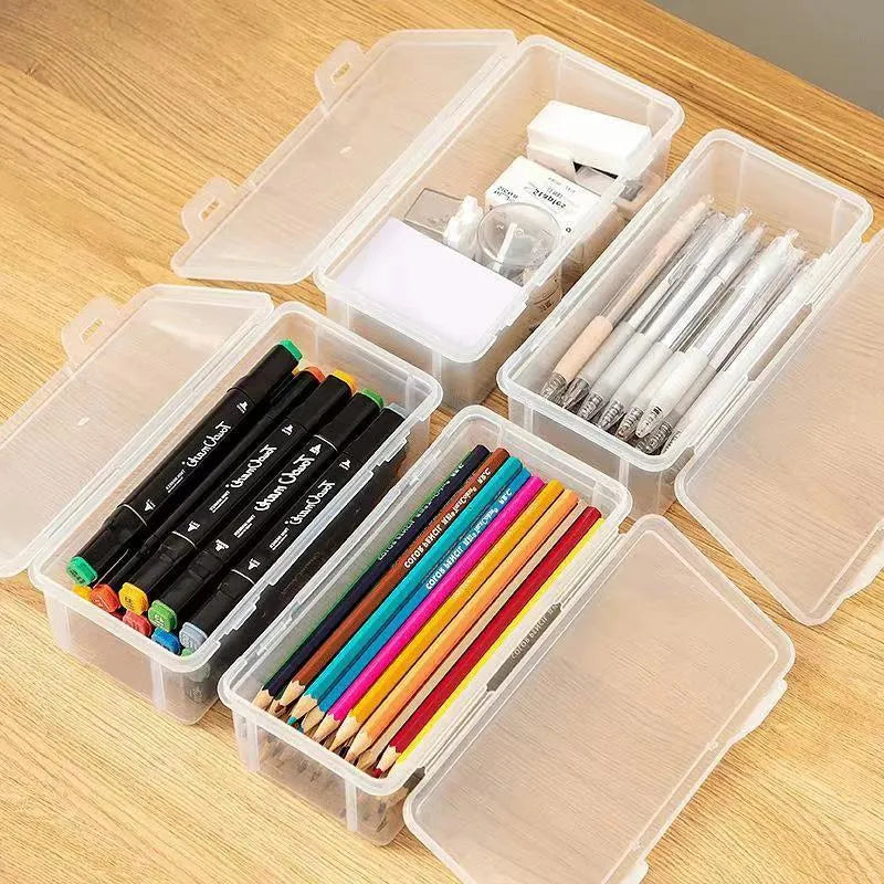 Clear plastic stationery storage box full of coloured pencils and drawing tools on a table.