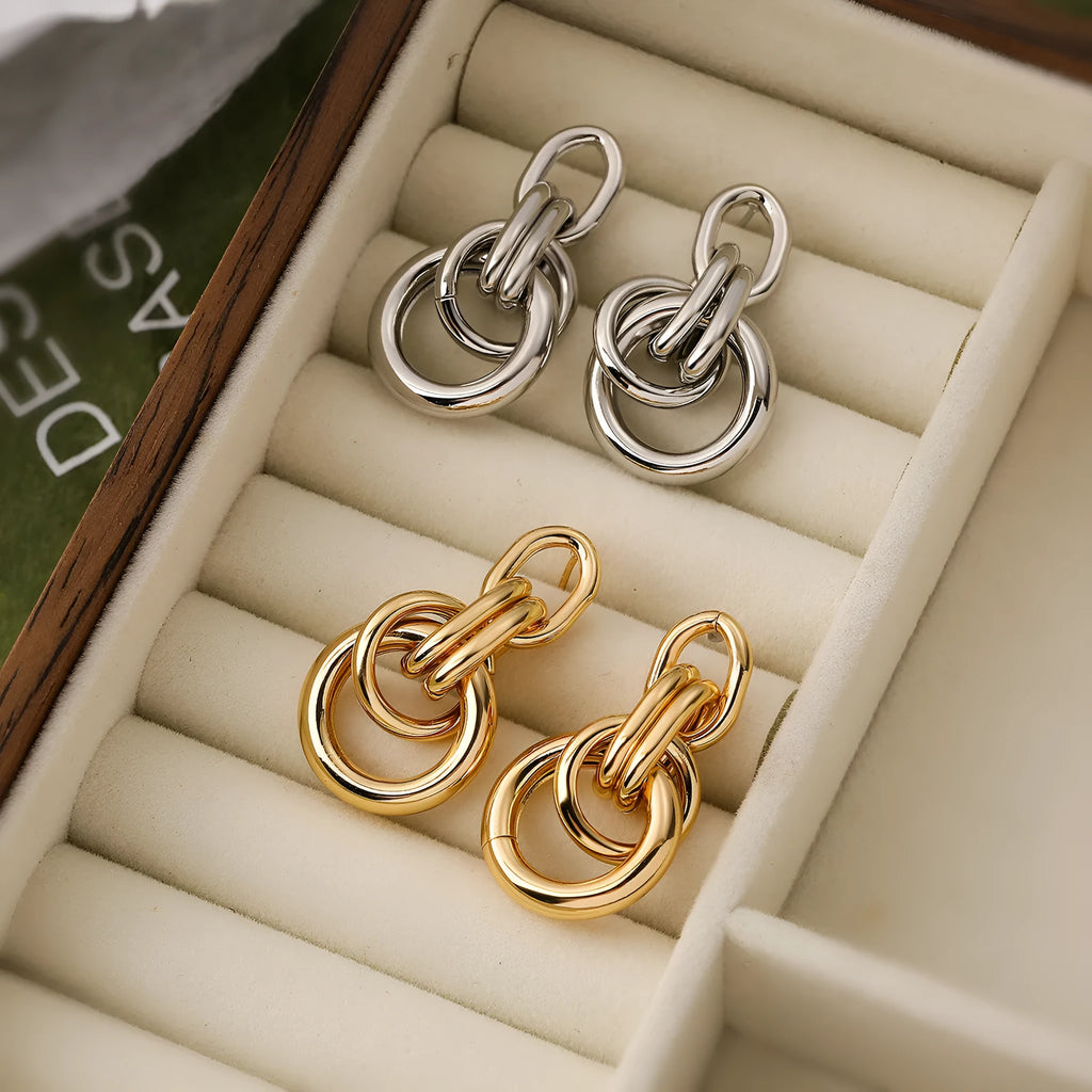 A pair of gold geometric drop earrings with an irregular asymmetric shape, made from copper.