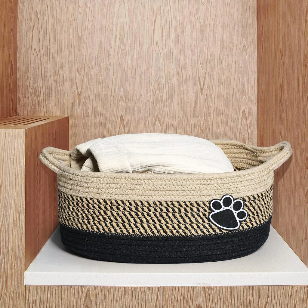 Light beige handmade cotton rope woven storage basket with handle on a wooden surface.