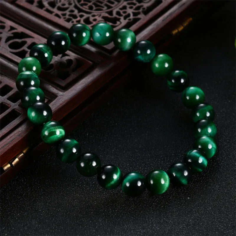 Green tiger eye stone bracelet with geometric polished beads on a wrist.