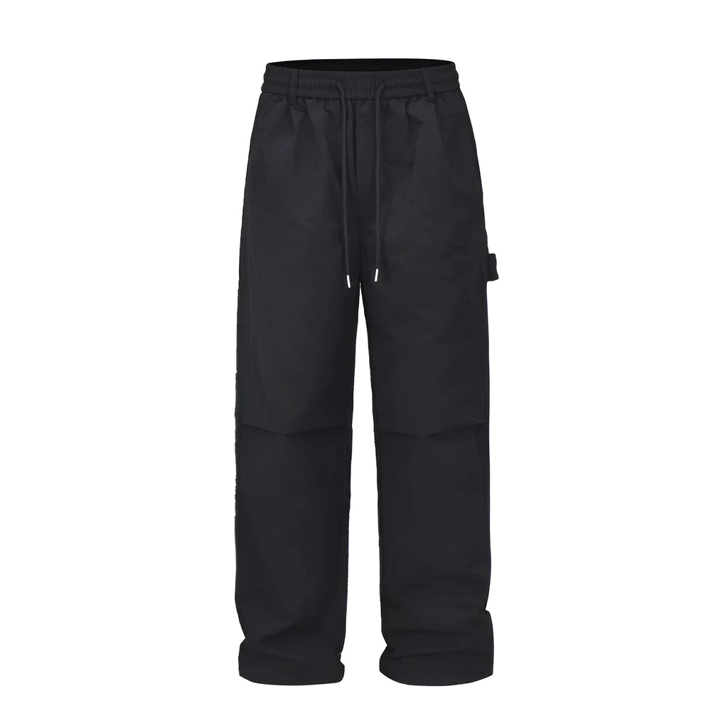 Men's baggy paratrooper pants in black with elastic waist and drawstring, side view on model